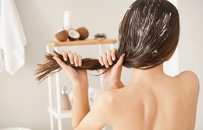 Woman applying coconut oil to manage dandruff.